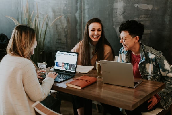 Sie sehen ein Screen unseres Kurses Employer Branding. Es sind drei junge Frauen an einem Tisch abgebildet, die zusammen arbeiten, miteinander reden und lachen.