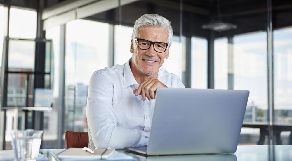 Sie sehen einen Mann der an einem Laptop sitzt und ein Learning Management System nutzt.