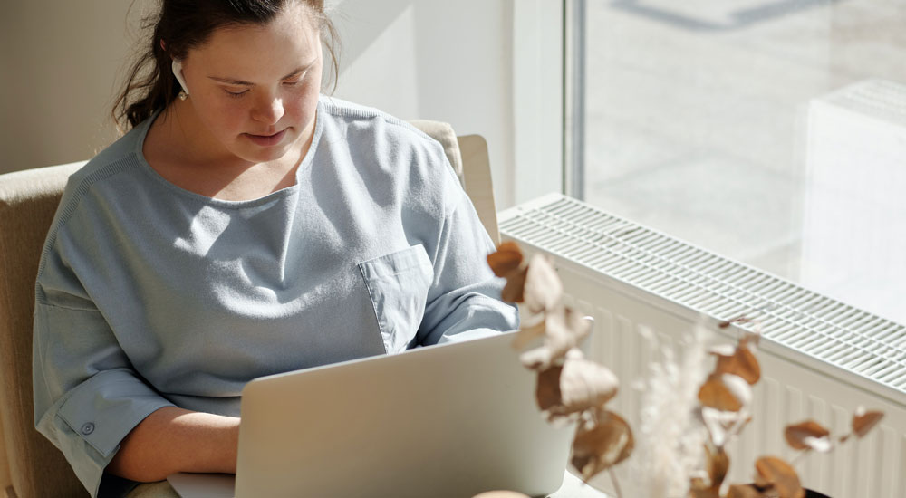 Sie sehen eine junge Frau mit einer Behinderung die eine barrierefreie Weiterbildungssoftware von M.I.T verwendet.